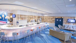 Un espace bar moderne avec un comptoir, des tabourets et des étagères remplies de bouteilles.