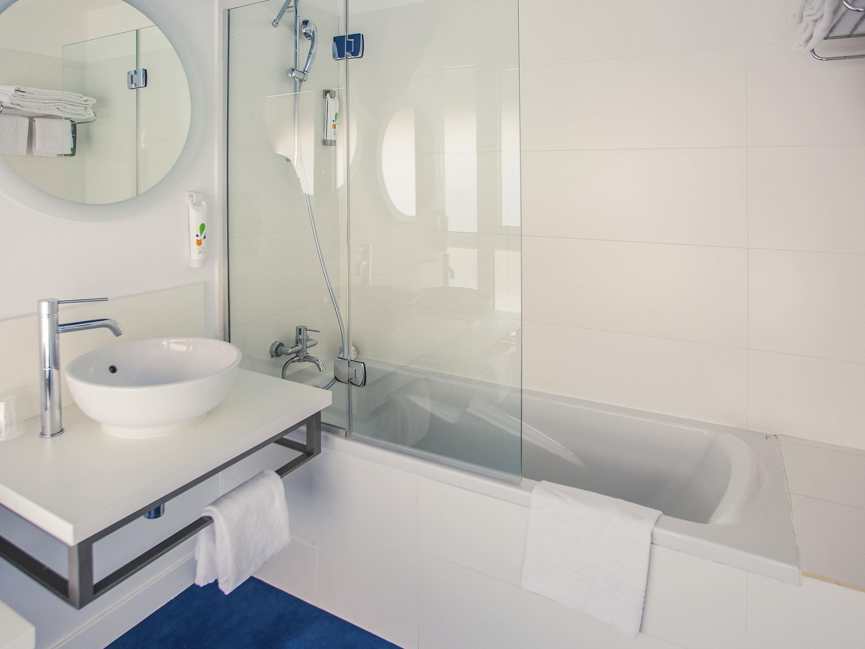 Un bagno moderno con doccia vetrata, lavandino bianco e vasca da bagno.