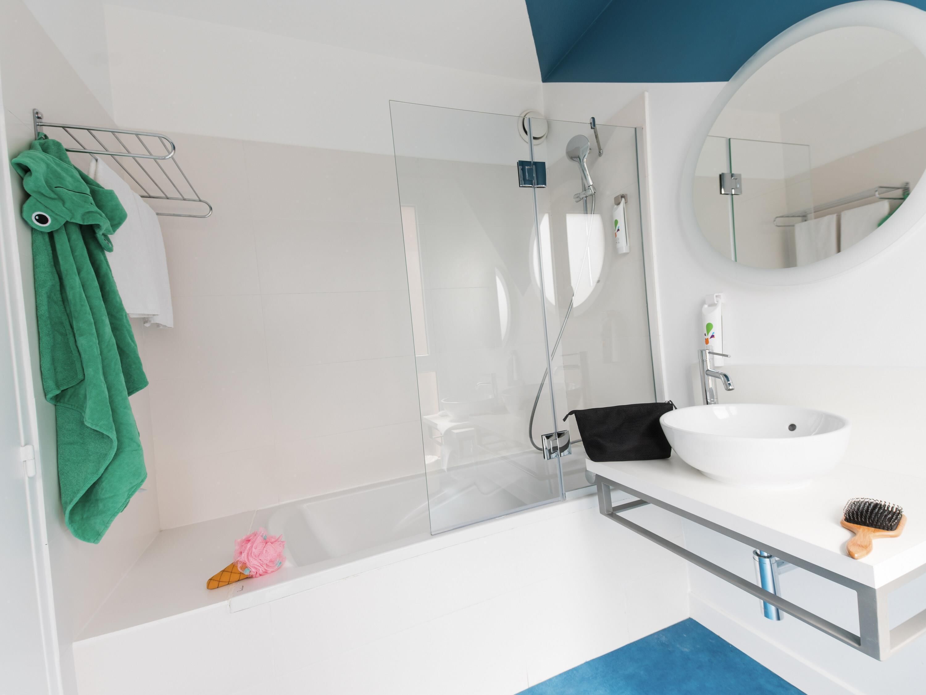 A modern bathroom with a glass shower enclosure, a white sink, and a mirror.