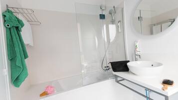 A modern bathroom with a glass shower enclosure, a white sink, and a mirror.