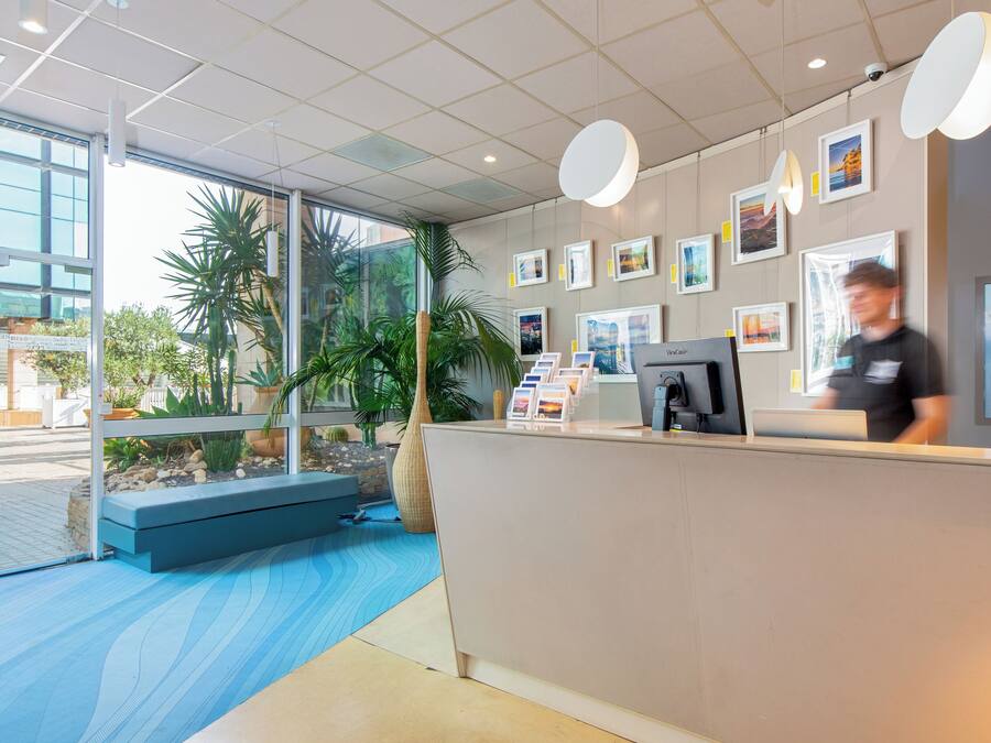A reception area with a glass wall, a reception desk, a computer, and framed pictures on the wall.