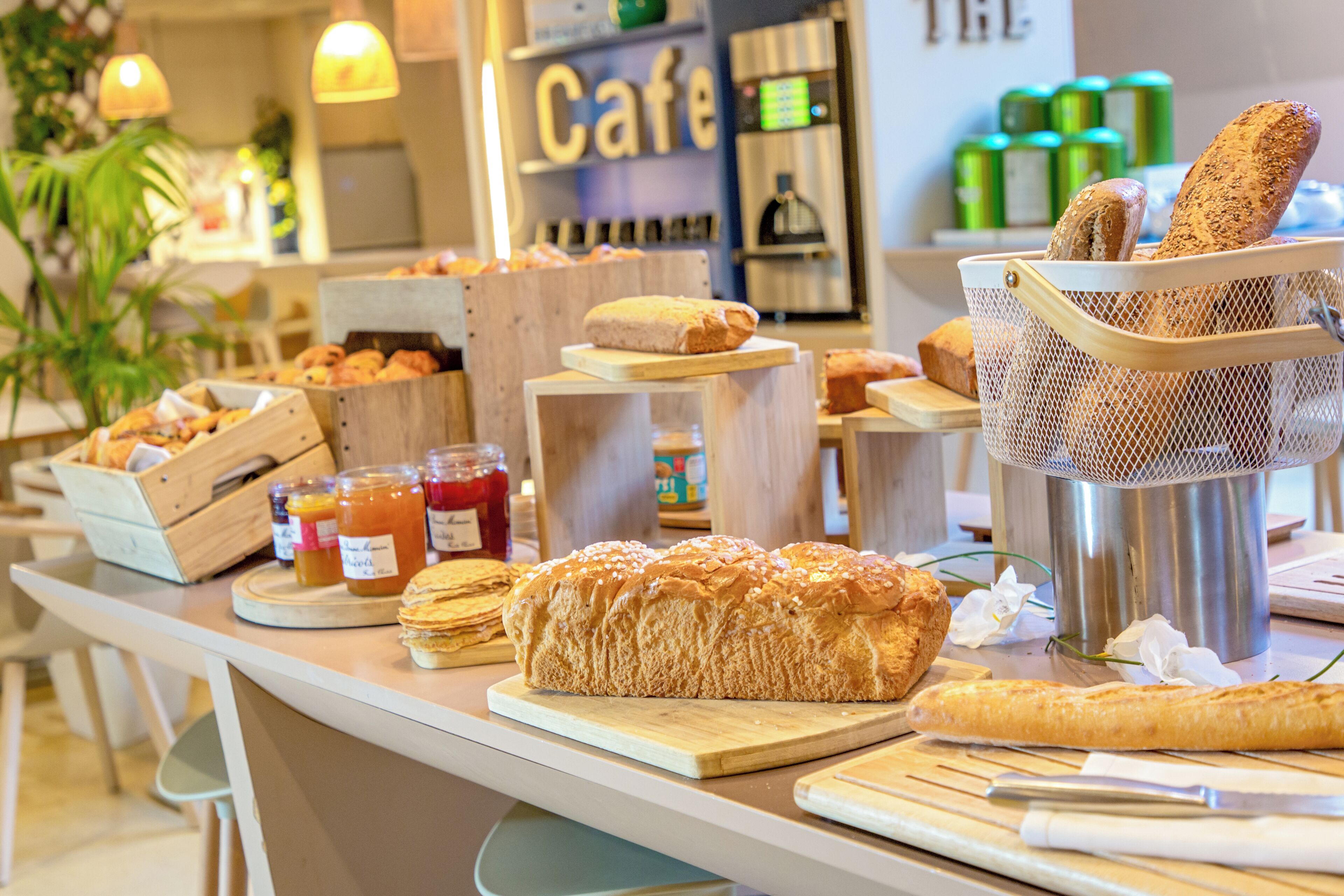 A bakery counter with various breads, pastries, and jars of spreads.
