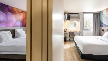 A hotel room with two beds, a desk, and a chair.