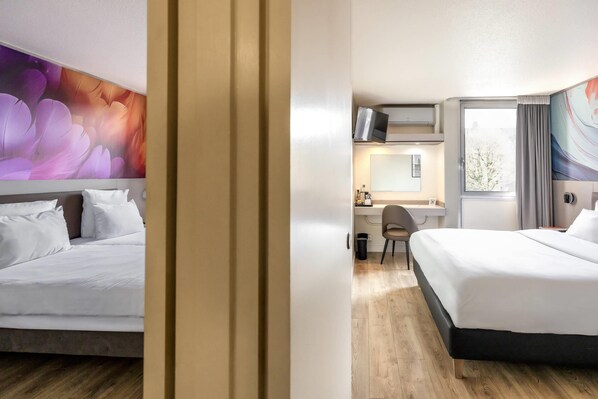 A hotel room with two beds, a desk, and a chair.