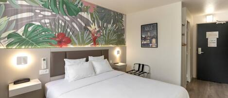 Una habitación de hotel con una cama, una mesita de noche, una lámpara de pared, una obra de arte en la pared y una puerta.
