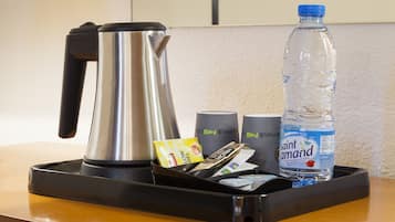 Ontbijttafel in een hotelkamer met een waterkoker, een fles Saint Amand water en diverse ontbijtartikelen.