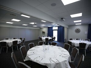 A conference room with round tables, chairs, and a projector.