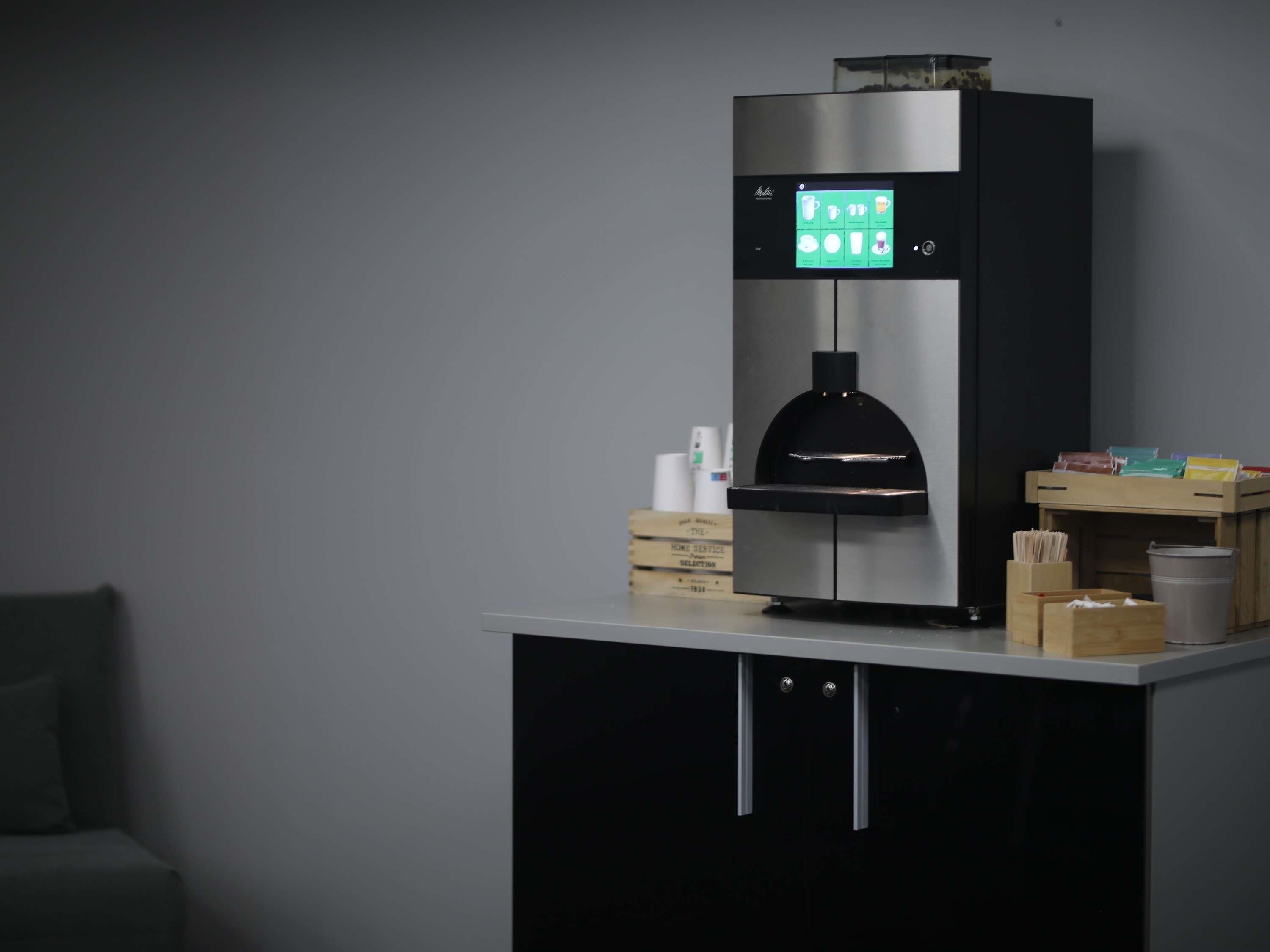 A modern coffee machine with a digital display, placed on a counter with a cabinet below.