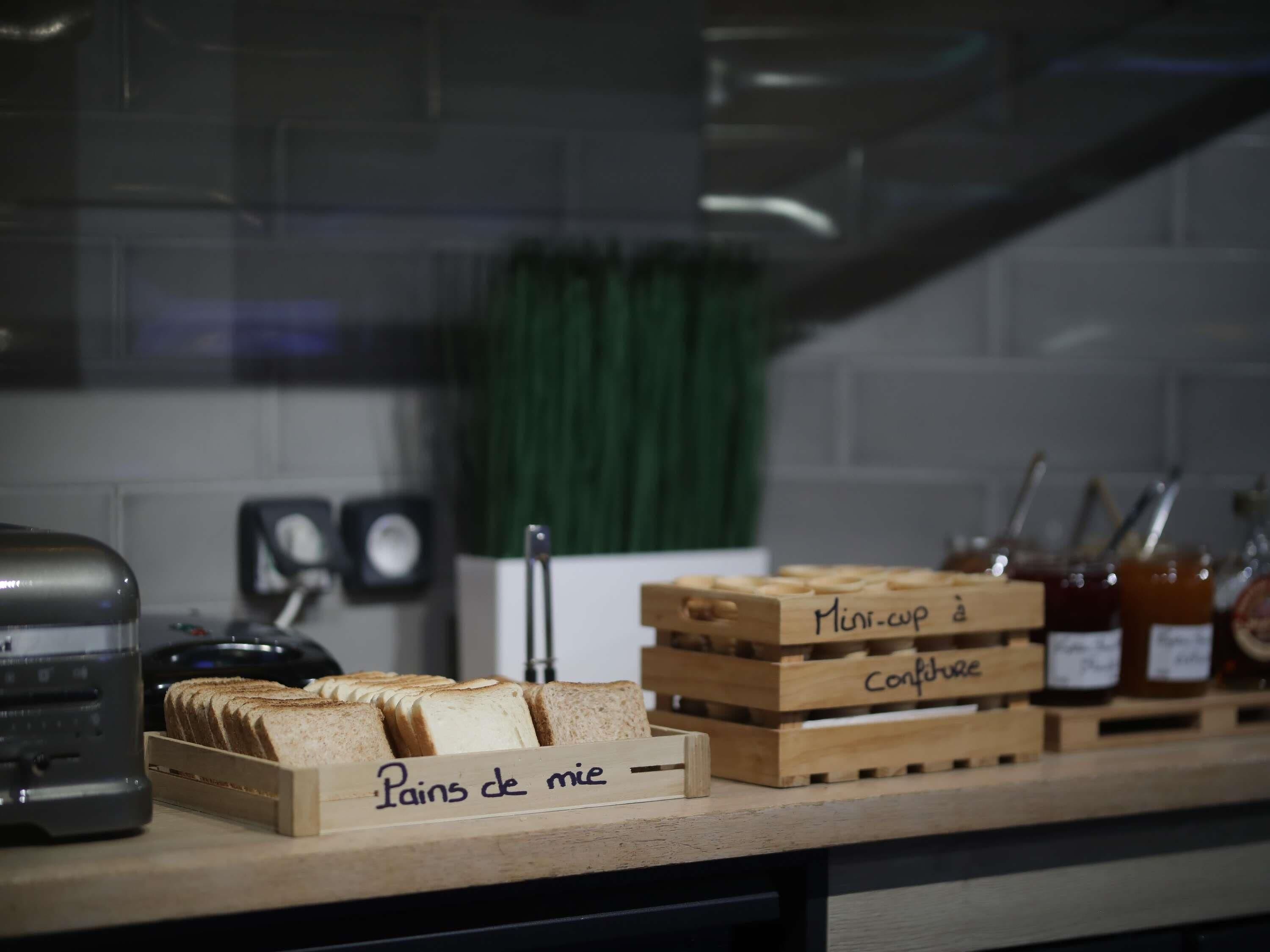 A kitchen counter with bread, jars of jam, and a coffee maker.