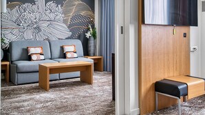 A modern living room with a grey sofa, wooden coffee table, and a large abstract wall mural. - Novotel Paris Charenton Le Pont  (Charenton-le-Pont)