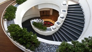 A circular atrium with a central seating area, surrounded by a spiral staircase. - Novotel Paris Charenton Le Pont  (Charenton-le-Pont)