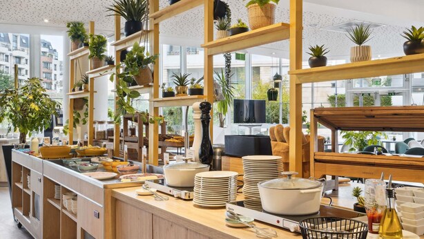 A buffet setup with various dishes, plates, and serving utensils. - Novotel Paris Charenton Le Pont  (Charenton-le-Pont)