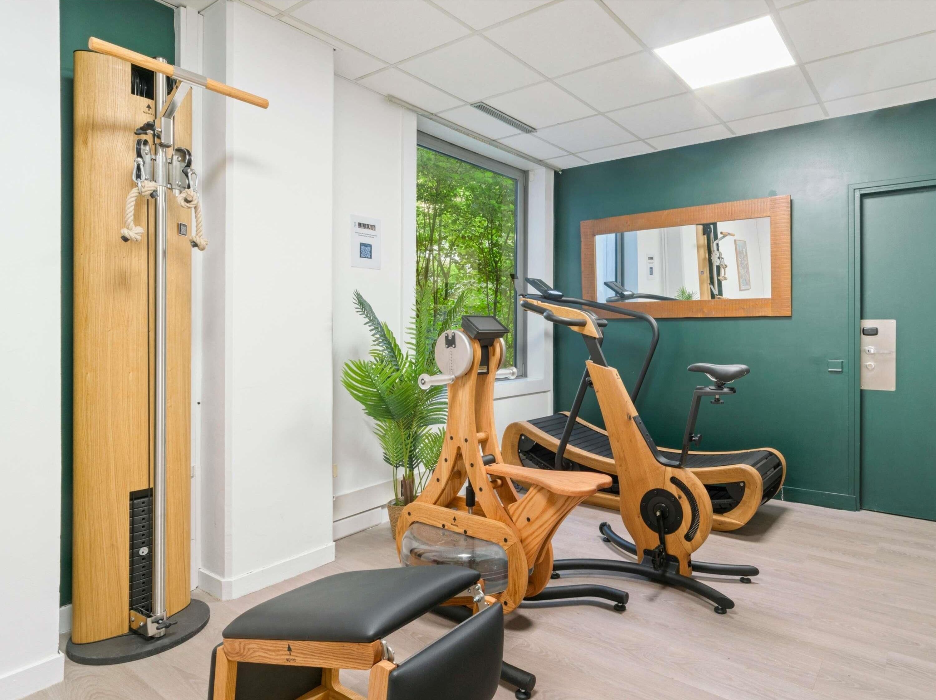 Un gimnasio con equipo de ejercicio de madera, una cinta de correr y una banca.