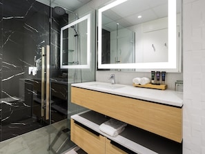 A modern bathroom with a glass-enclosed shower, a white vanity with a mirror, and a wooden cabinet.