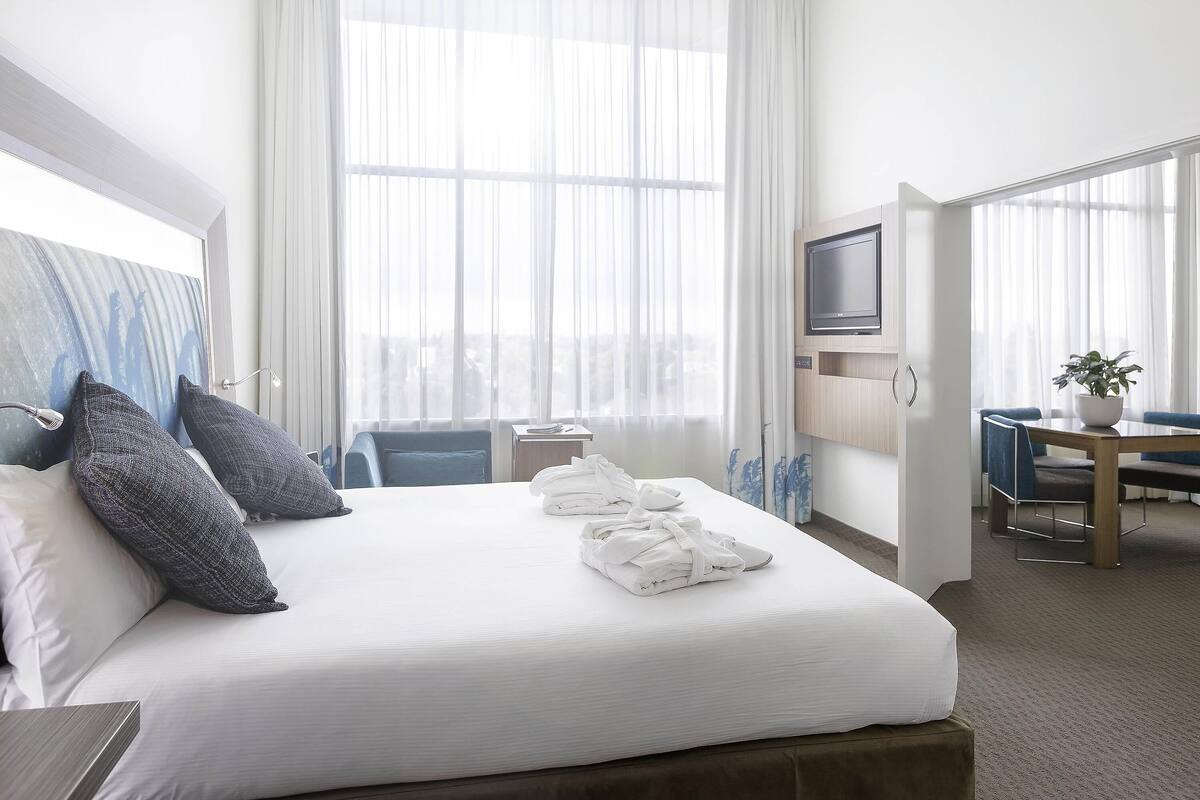 A hotel room with a bed, a desk, a chair, a television, and a window with curtains.