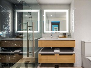 A modern bathroom with a glass-enclosed shower, a large mirror, and a wooden vanity.