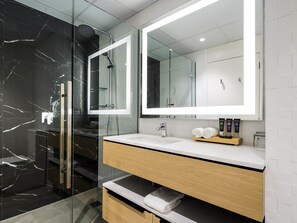 A modern bathroom with a glass-enclosed shower, a large mirror, and a wooden vanity with a sink.
