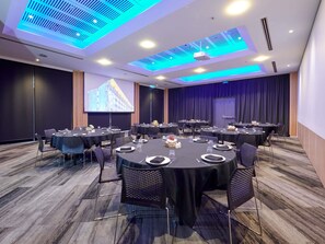 A conference room with round tables, chairs, a projector screen, and a presentation screen. - Novotel Tainui Hamilton (Hamilton)