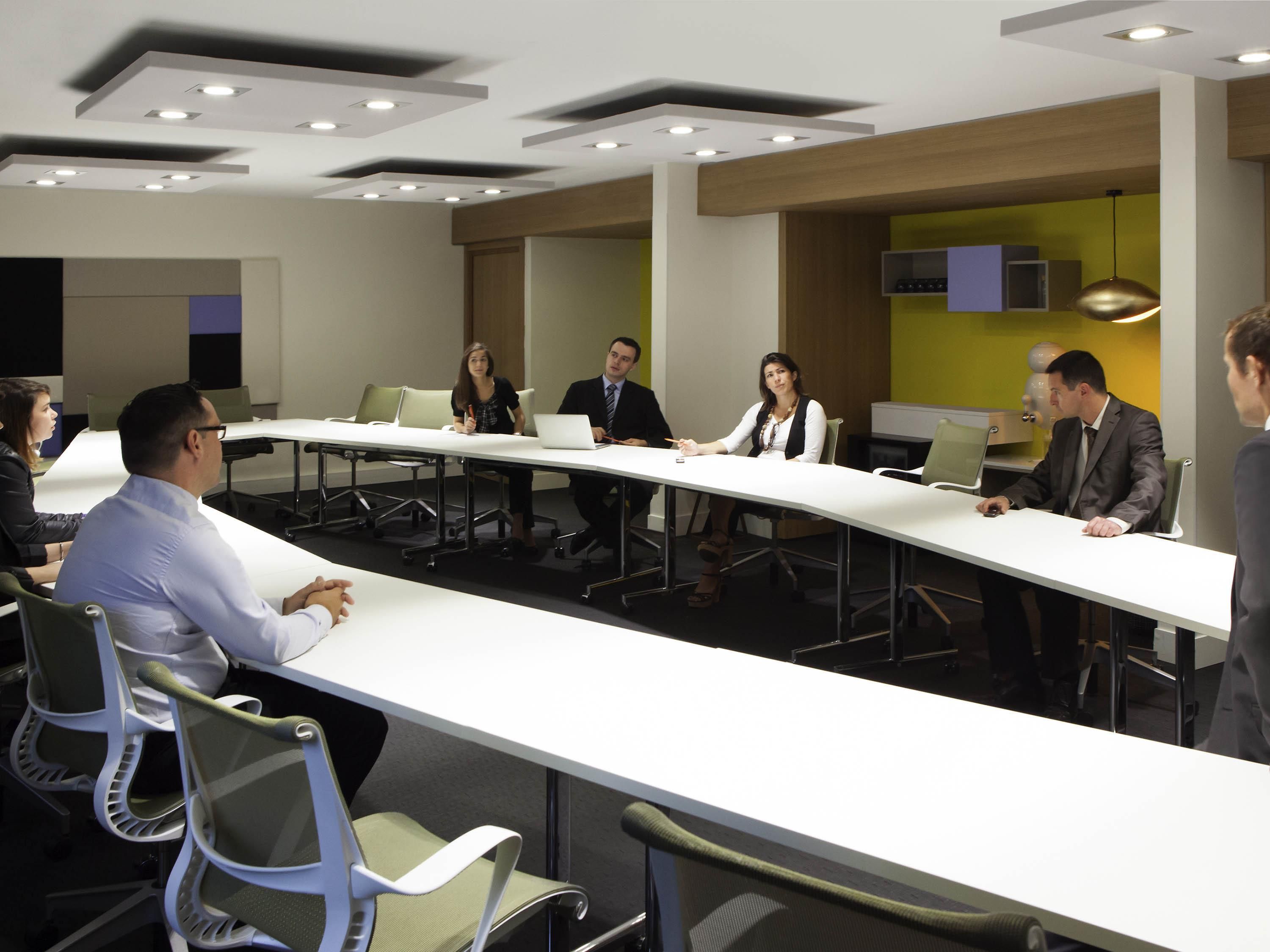 A conference room with a long table, chairs, and ceiling lights.