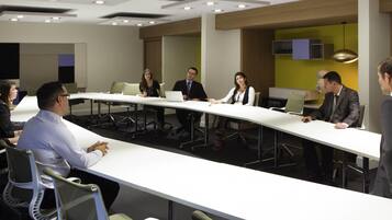 A conference room with a long table, chairs, and ceiling lights.