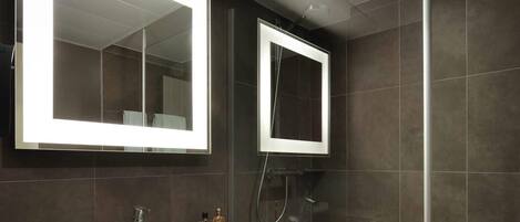 Une salle de bain moderne avec un grand miroir, un lavabo et une douche.