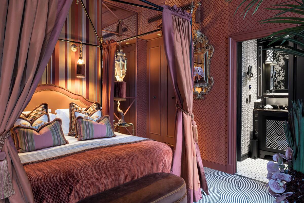 Un dormitorio lujoso con una cama grande, cortinas ornamentales y un candelabro decorativo.