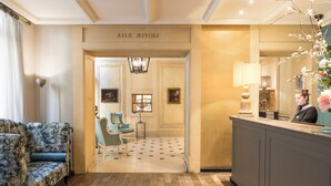 A lobby with a reception desk, a blue armchair, and a chandelier.