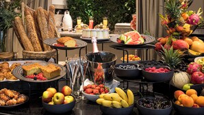 A buffet with various fruits, vegetables, and pastries.