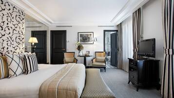 Habitación de hotel con una cama grande, un escritorio con lámpara, televisión y una silla.