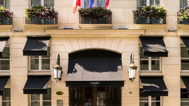Fachada de hotel con varios balcones, banderas francesa e italiana, y un cartel con el nombre y la dirección.