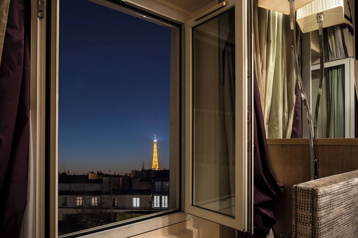 Una habitación con vista a la Torre Eiffel de noche.