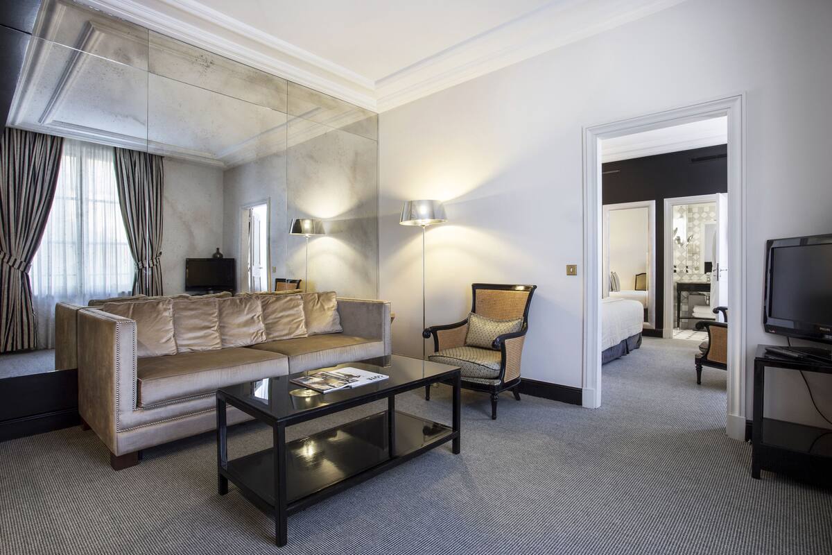 Una habitación de hotel con sofá, sillón y televisor.