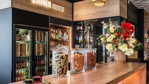 Een barruimte met een bord waarop 'CORNER STATION' staat, planken met flessen, een presentatie van noten en een bloemstuk.