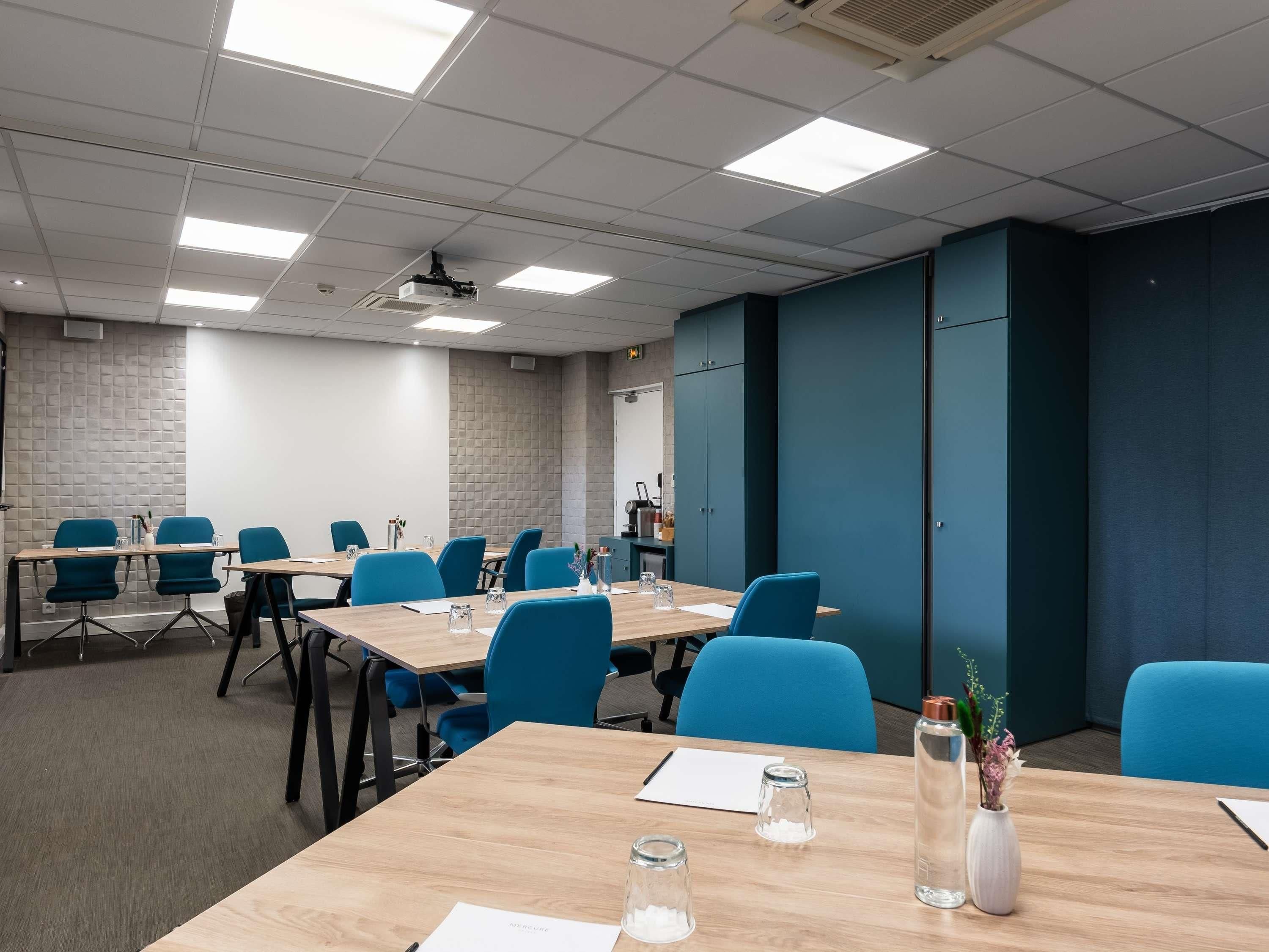 A conference room with tables, chairs, and a projector.