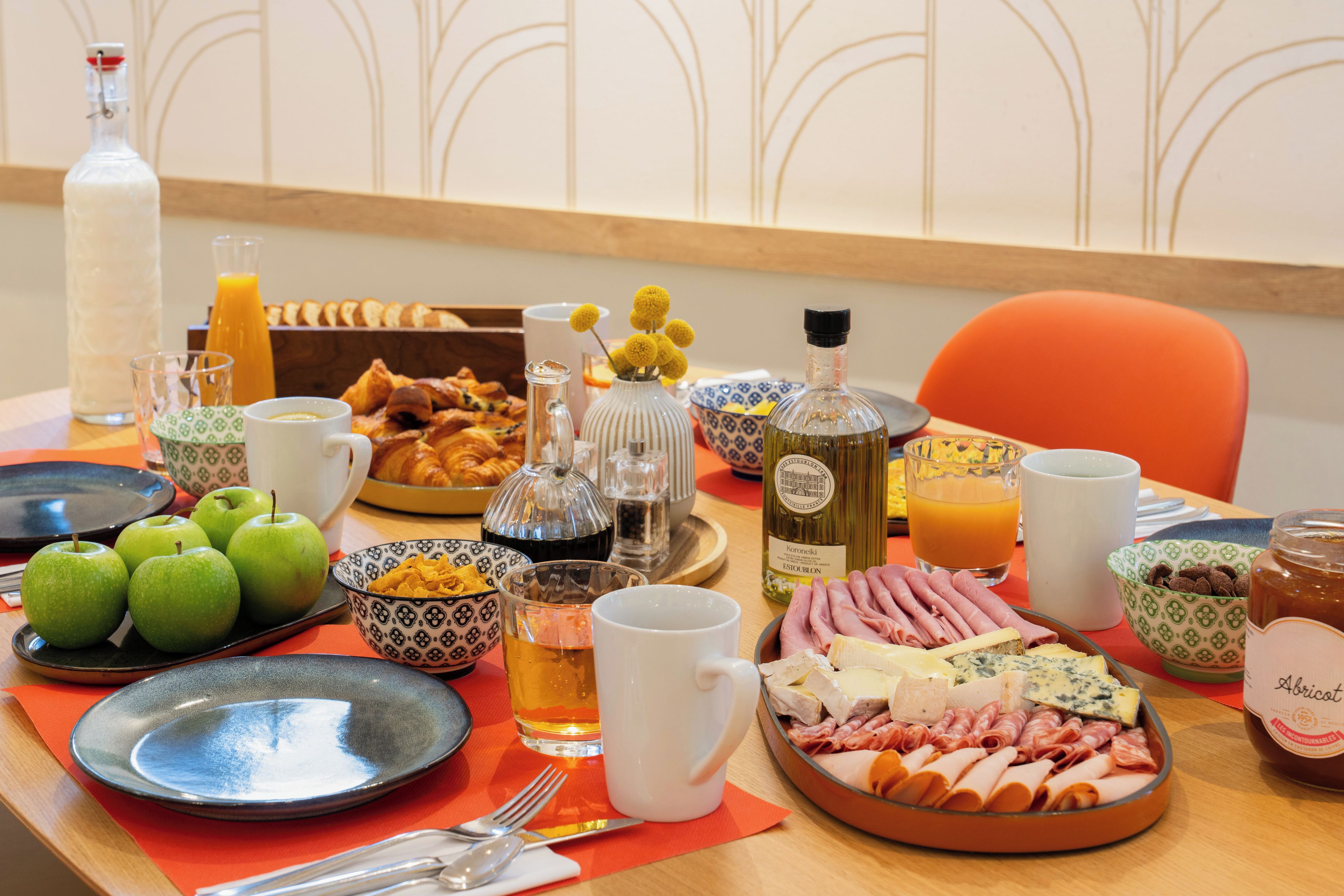 Una mesa dispuesta con diversos alimentos, como manzanas, queso y carnes, además de bebidas y salsas.