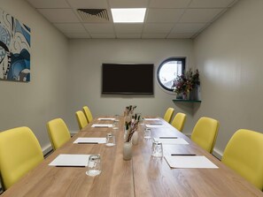A conference room with a long table, yellow chairs, a large screen, and a window with a view. - Mercure Paris Gare De Lyon TGV (Paris)