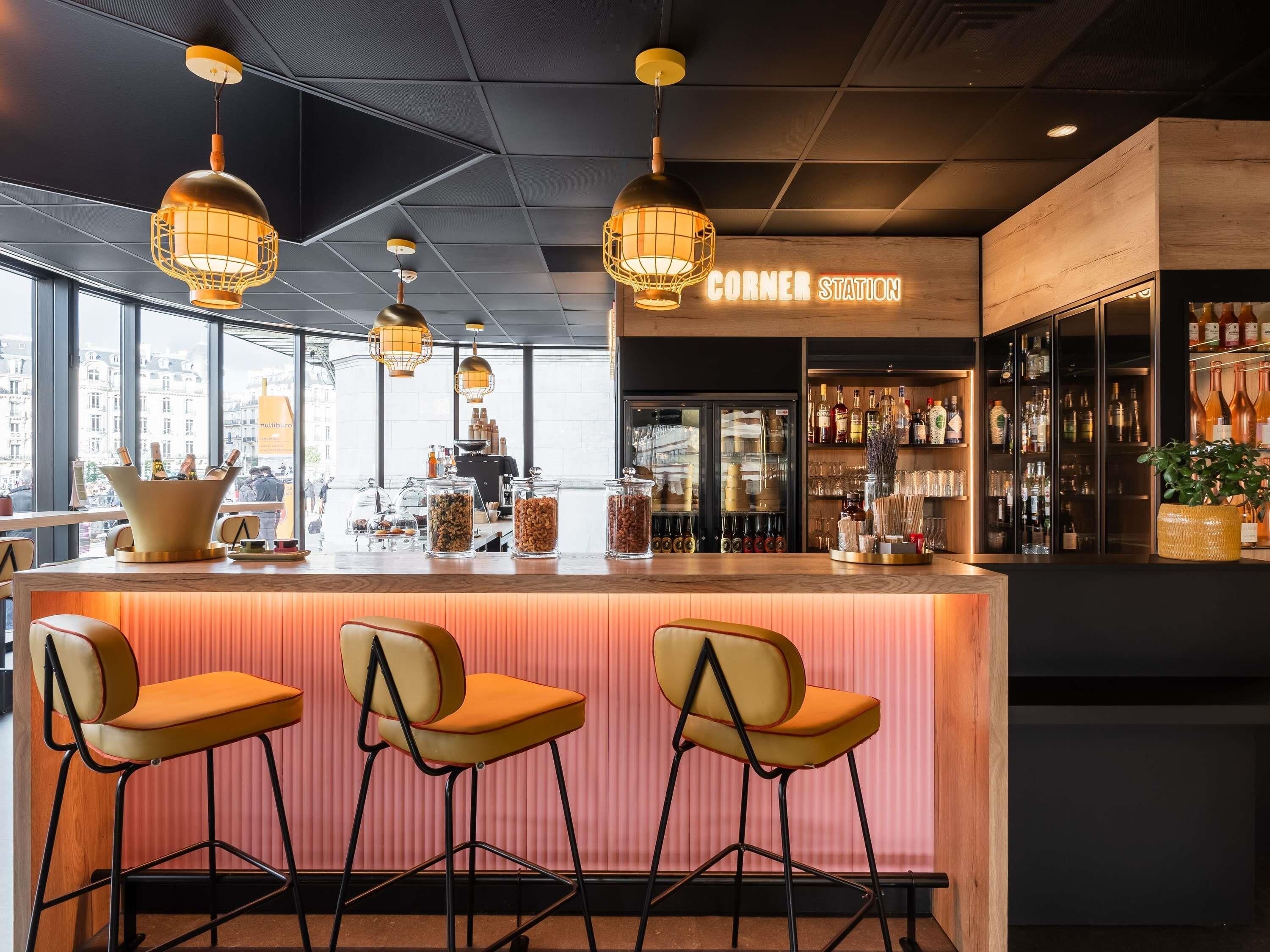A bar area with a wooden counter, three bar stools, and hanging pendant lights.