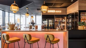 A bar area with a wooden counter, three bar stools, and hanging pendant lights.