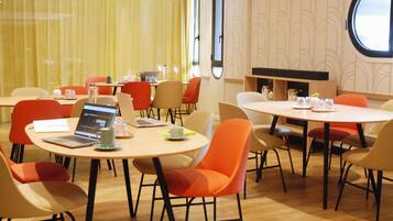A conference room with round tables, chairs, laptops, and a large window.