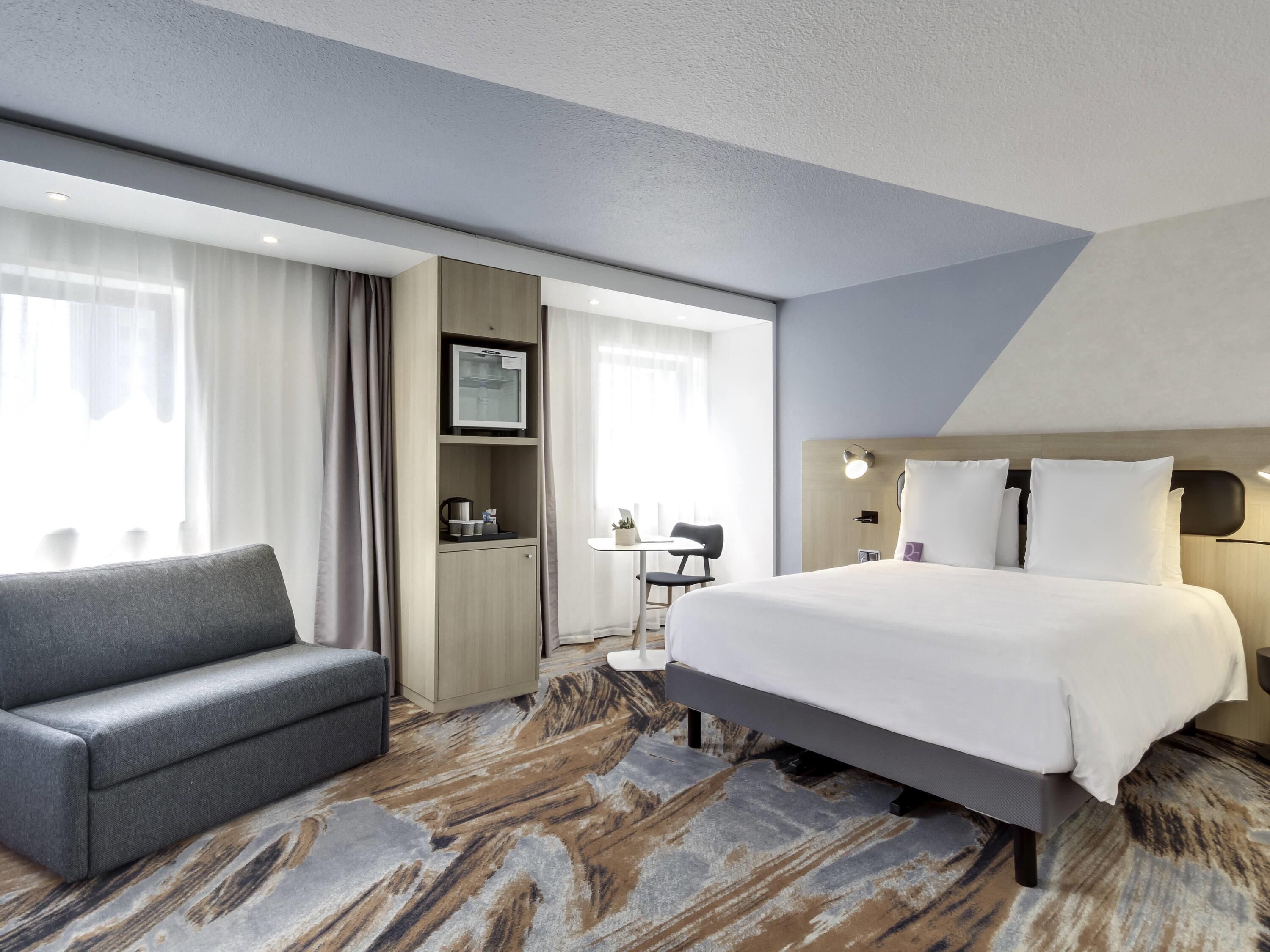 Une chambre d’hôtel avec un lit, un canapé, un bureau et une télévision.