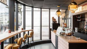 A modern cafe with a bar area, seating, and a view of the street.