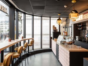 A modern cafe with a bar area, seating, and a view of the street. - Mercure Paris Gare De Lyon TGV (Paris)