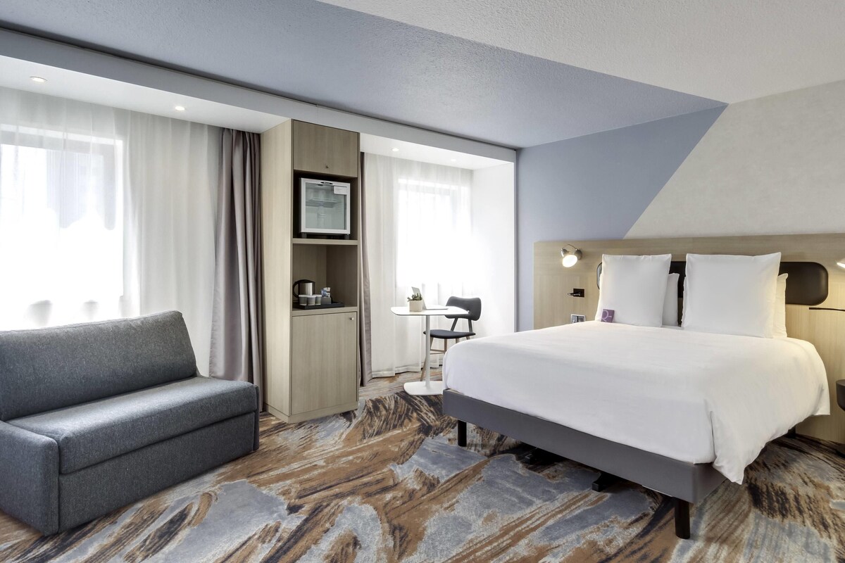 Een hotelkamer met een bed, een slaapbank, een bureau en een televisie.