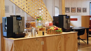 A buffet area with coffee machines, a fruit display, and a coffee station.