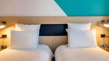 Une chambre d’hôtel avec deux lits, une tête de lit en bois, des lampes de chevet et un téléviseur fixé au mur.