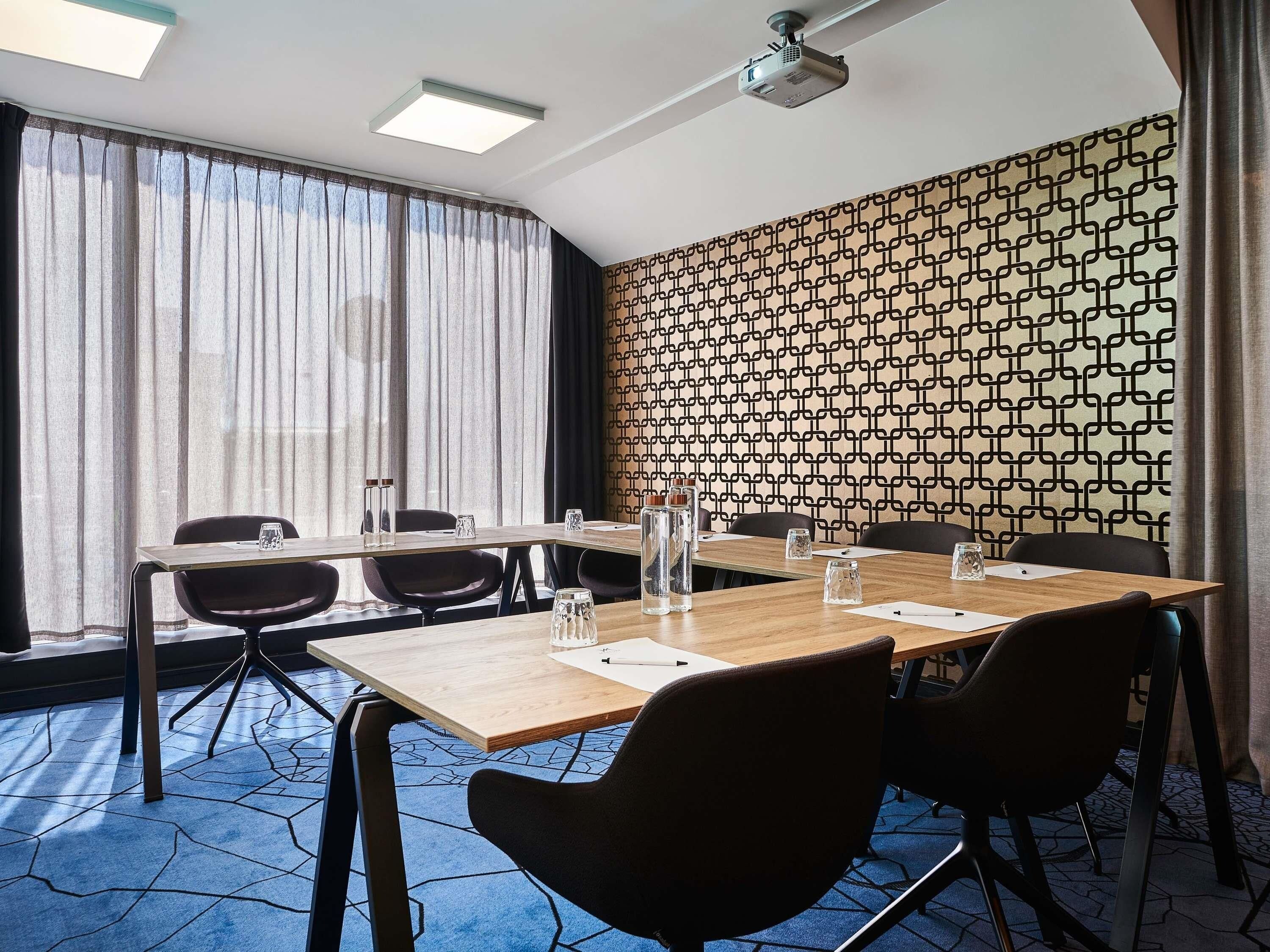 Une salle de conférence avec une longue table, des chaises et un projecteur.