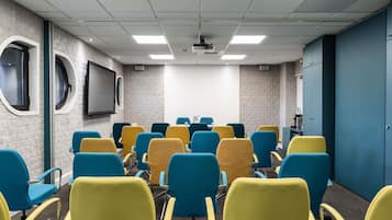 Un salón de conferencias con techo blanco, paredes de ladrillo gris y una puerta azul.