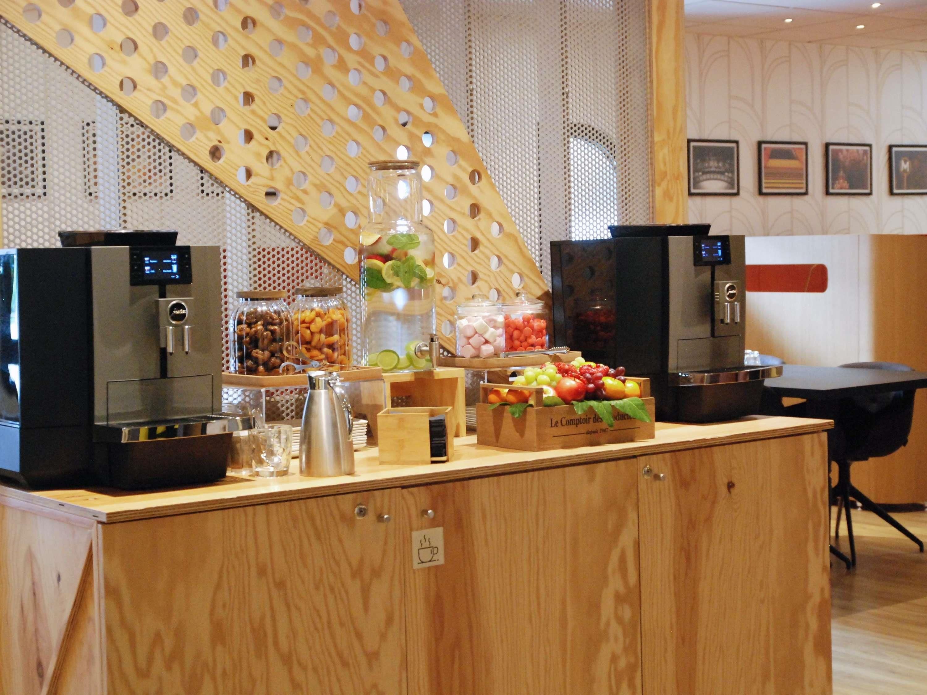 A breakfast bar with coffee machines, a fruit display, and a coffee urn.