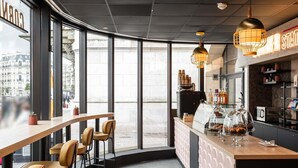 A modern café with large windows, a bar area, and a coffee machine. - Mercure Paris Gare De Lyon TGV (Paris)