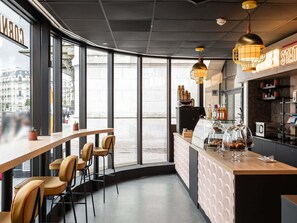 A modern café with large windows, a bar area, and a coffee machine. - Mercure Paris Gare De Lyon TGV (Paris)